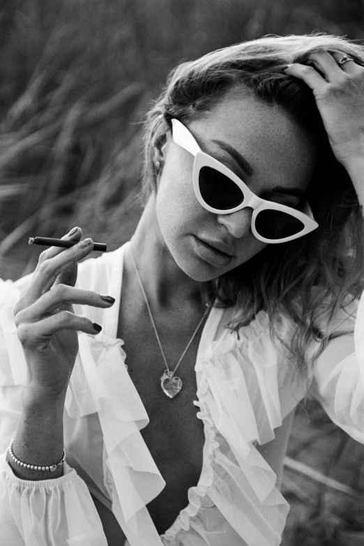 a woman in sunglasses holds a cigarette