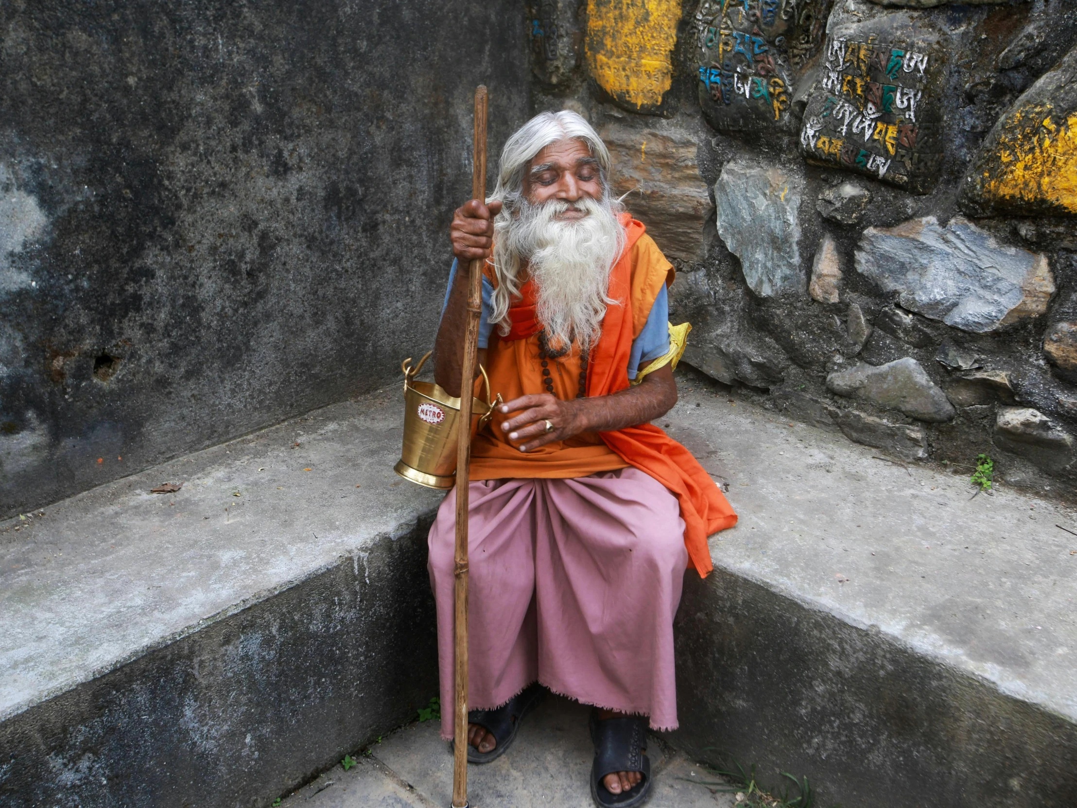 an old man with long gray hair and orange beard sits on the stairs