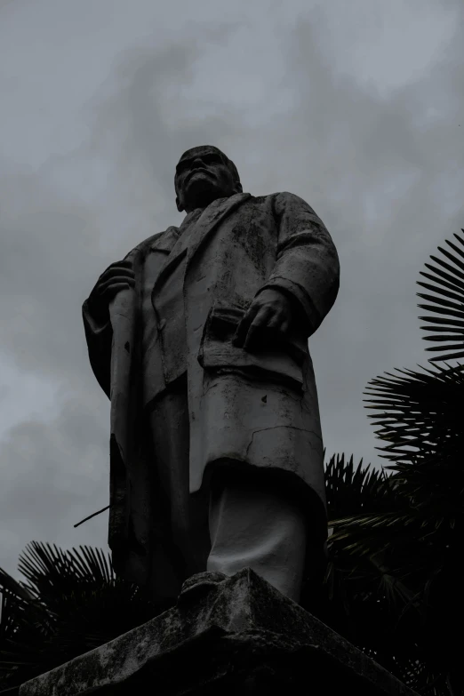 the statue is next to leaves, with cloudy sky in the background