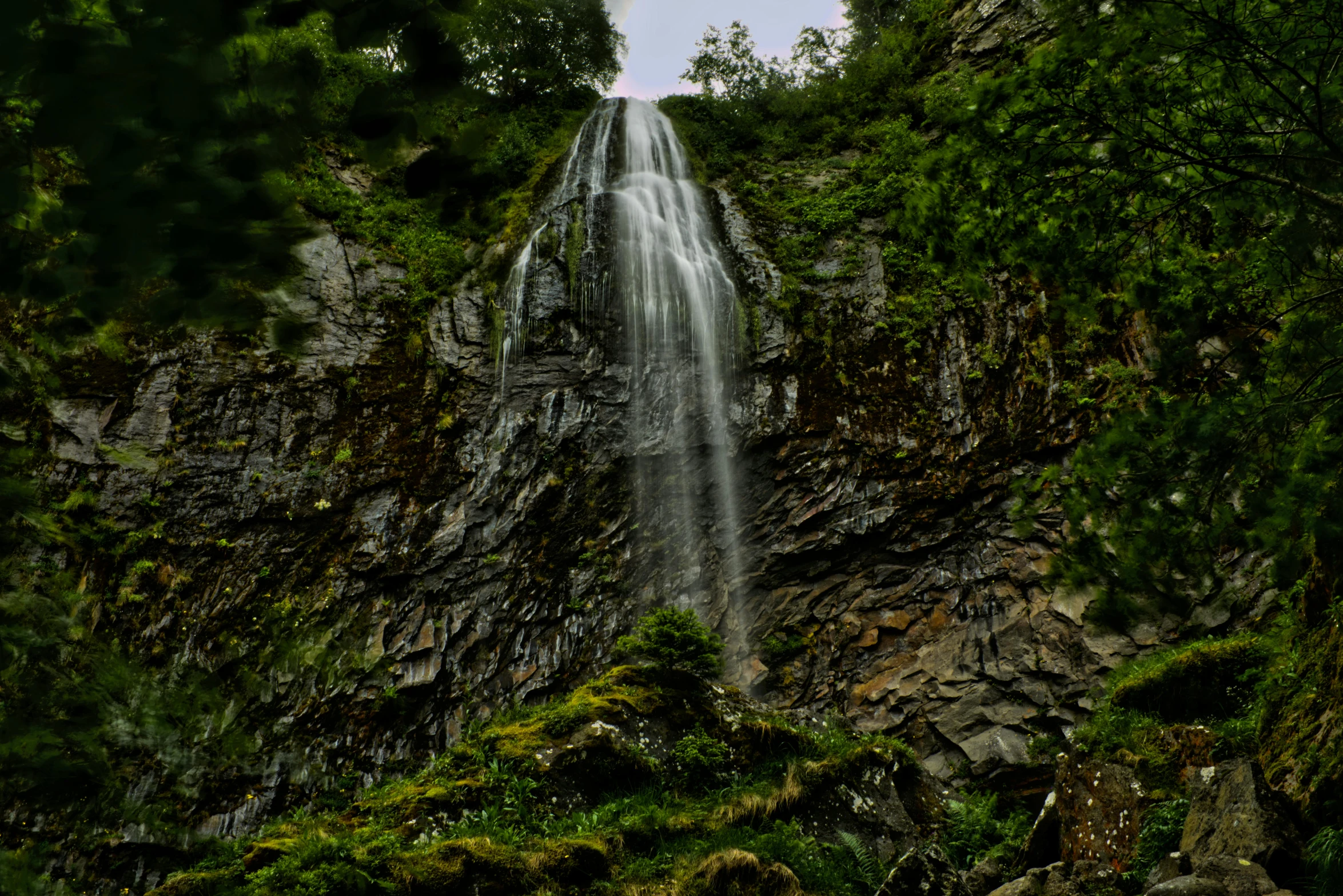 a very pretty waterfall near a big grassy hill