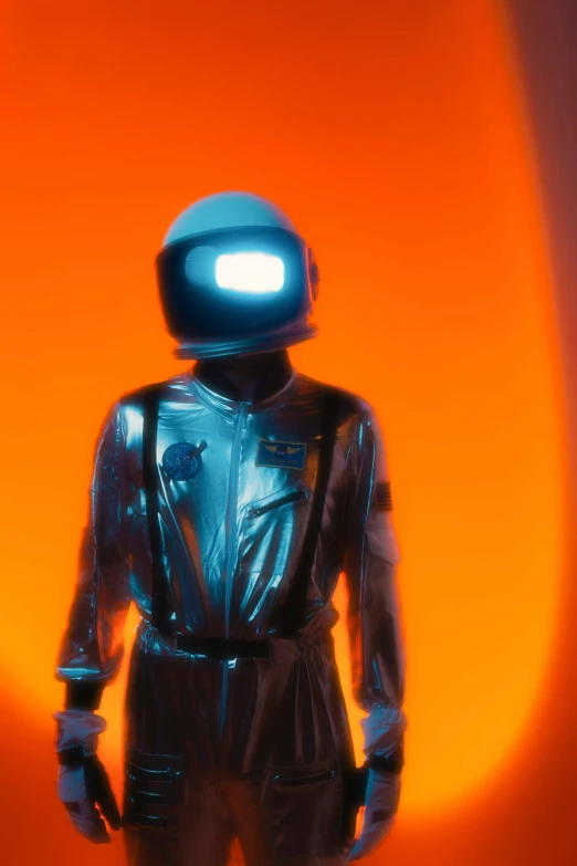 a person standing in front of a orange wall with a blue helmet and light