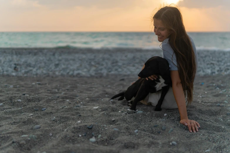 a girl laying down with a dog on the beach