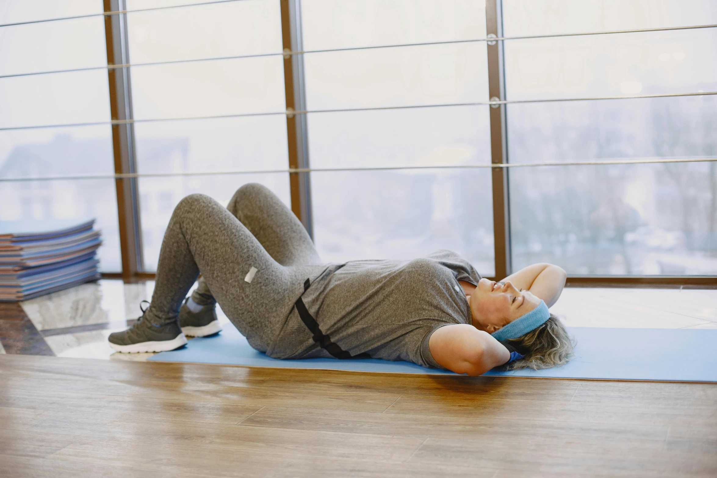 a female in grey shirt and gray pants is on a blue mat