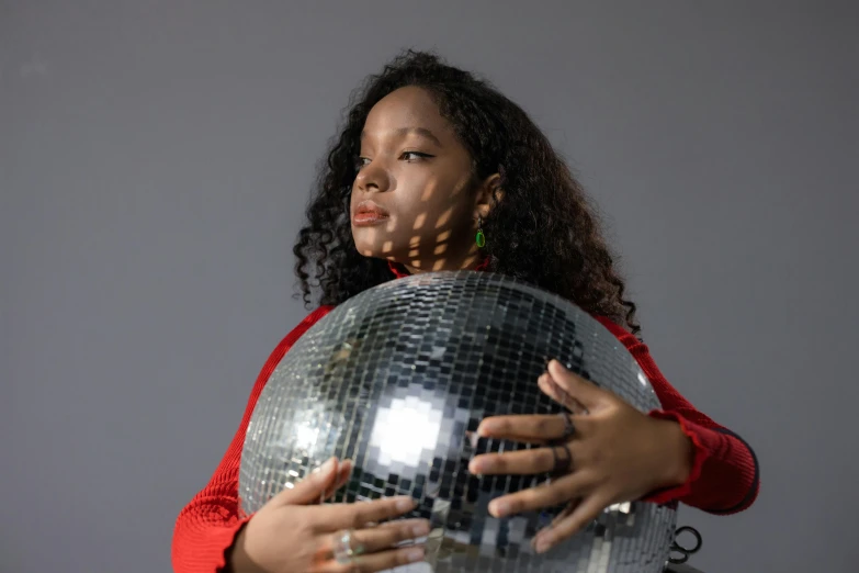 a woman holding onto a disco ball that is in her arms