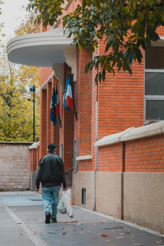 a man walks past flags hanging from a building