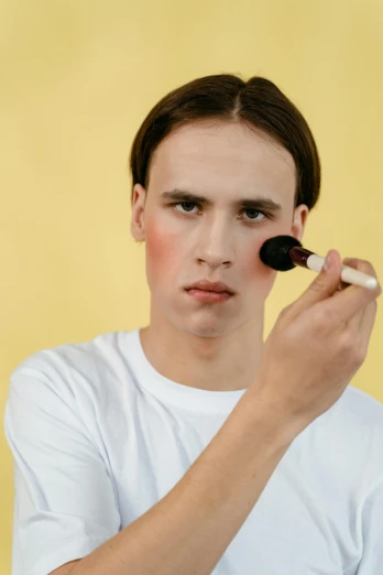 a boy wearing white tee shirt and make up brush