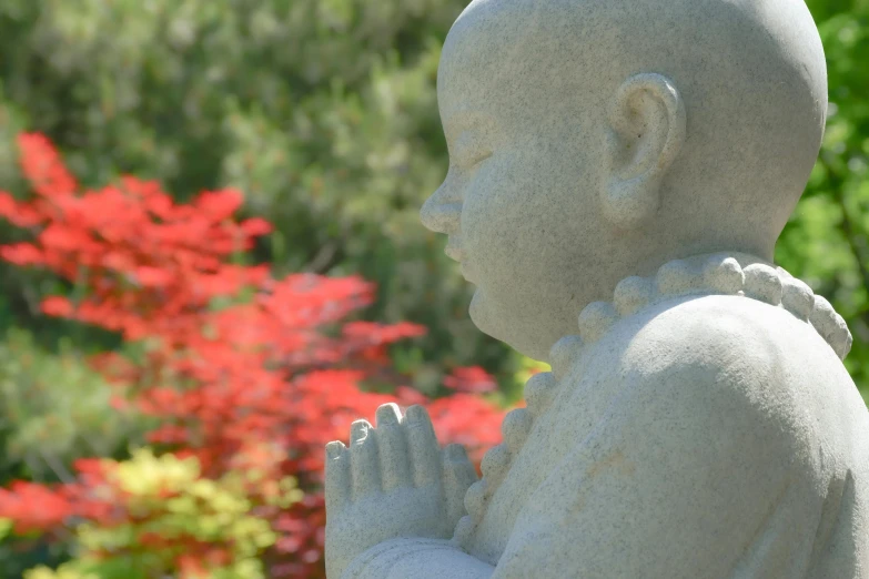 a statue in a garden that is holding a small white figure