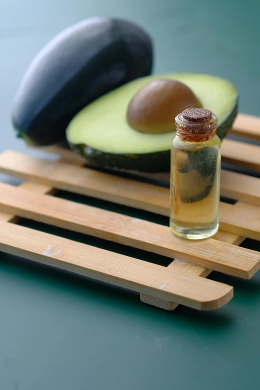 avocado, oil and some fruit are on a board