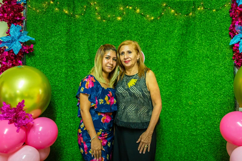 two women standing in front of a green backdrop