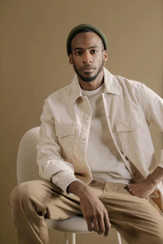 a man in a shirt and khaki pants sitting on a chair