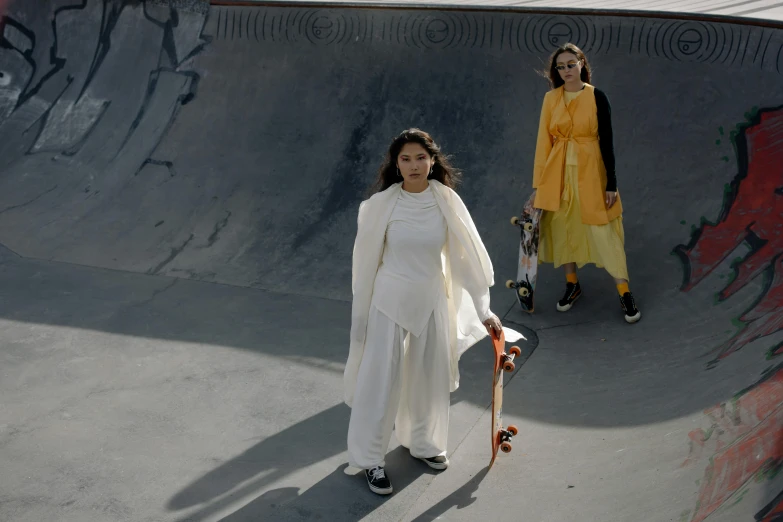two women are standing next to each other near the skateboard ramp