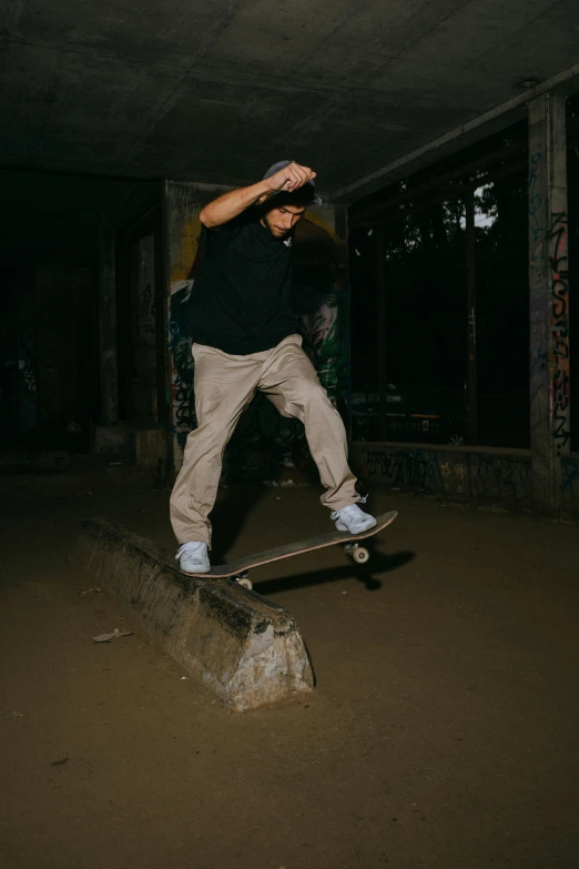 a man in black shirt jumping over a cement block on skateboard