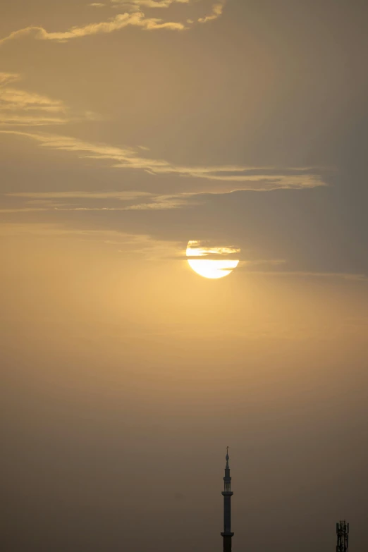 the sun is setting in the horizon behind some structures