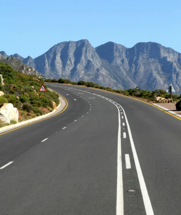 there is a long empty road in front of the mountains