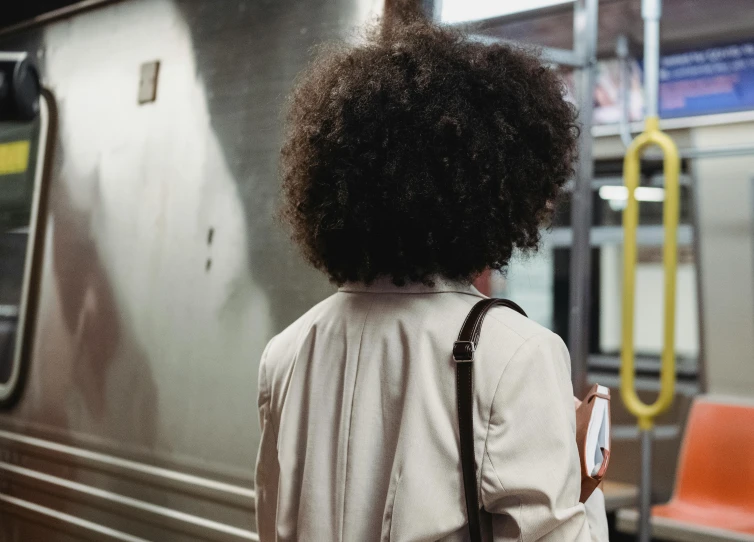 a woman standing at a subway station with a back pack