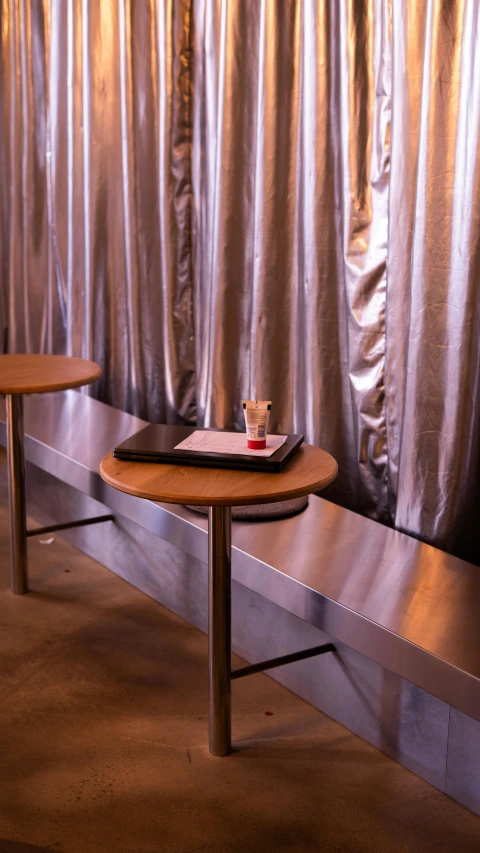 a table and two benches in front of a metal backdrop