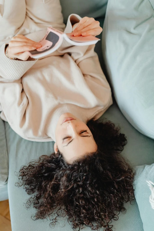 a woman laying on the couch holding her cell phone