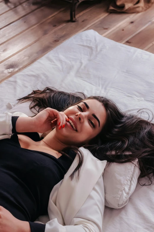 a girl laying on a bed while talking on a phone