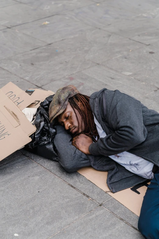 a man lays on his side next to a cardboard box