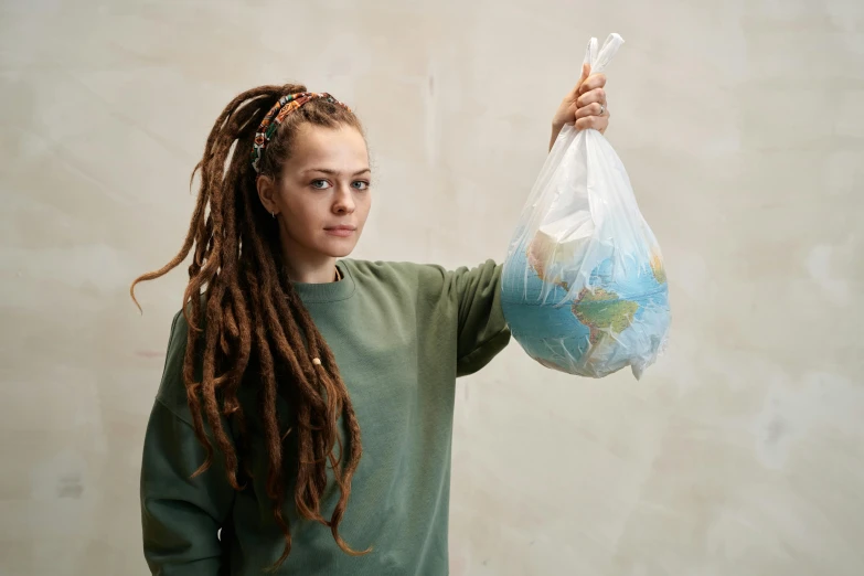 a woman in green holding a plastic bag with a map in it