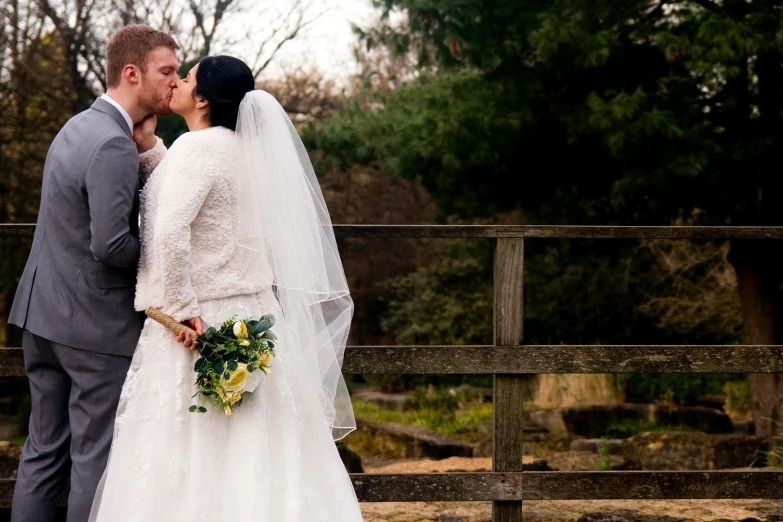 a bride and groom emcing in a park