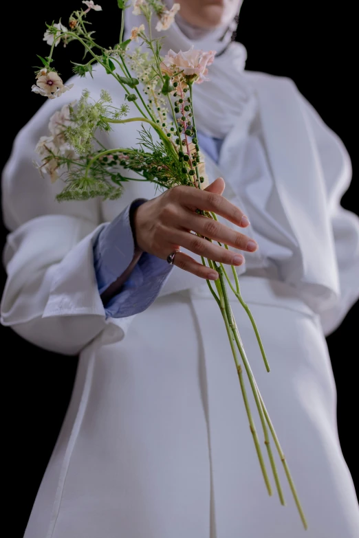 a woman in white shirt and white pants holding flowers