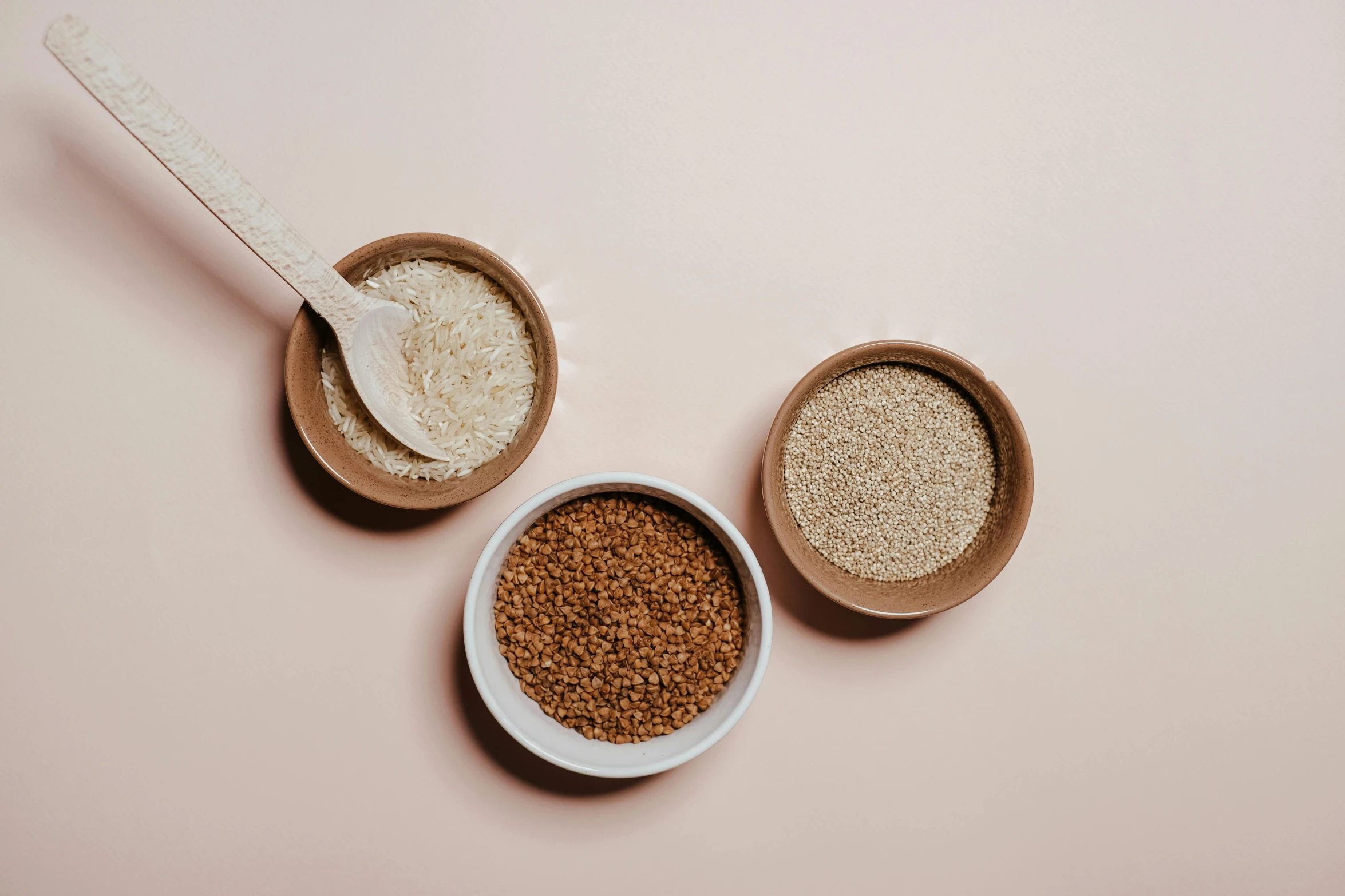 three bowls of food on a pink background