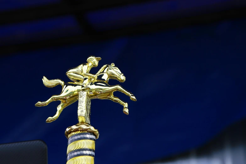 a golden pole has a horse and rider on it