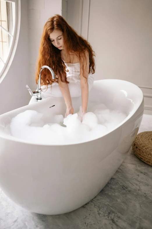 the redhead haired girl washes her hands in the bathtub