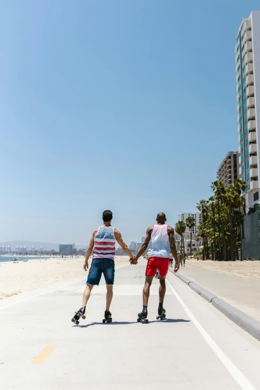 a couple of people holding hands while riding skateboards