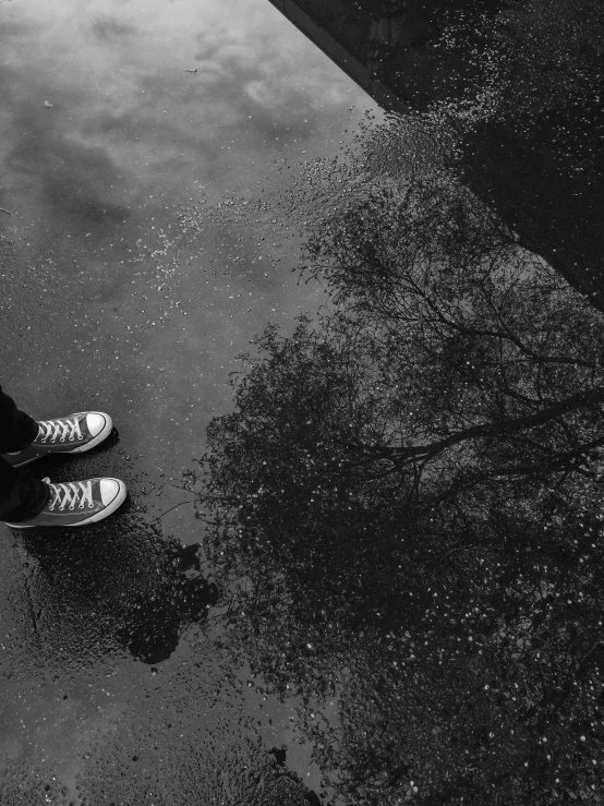 a black and white pograph of someone standing next to water