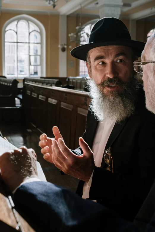 a rabbi talking to two men in pews