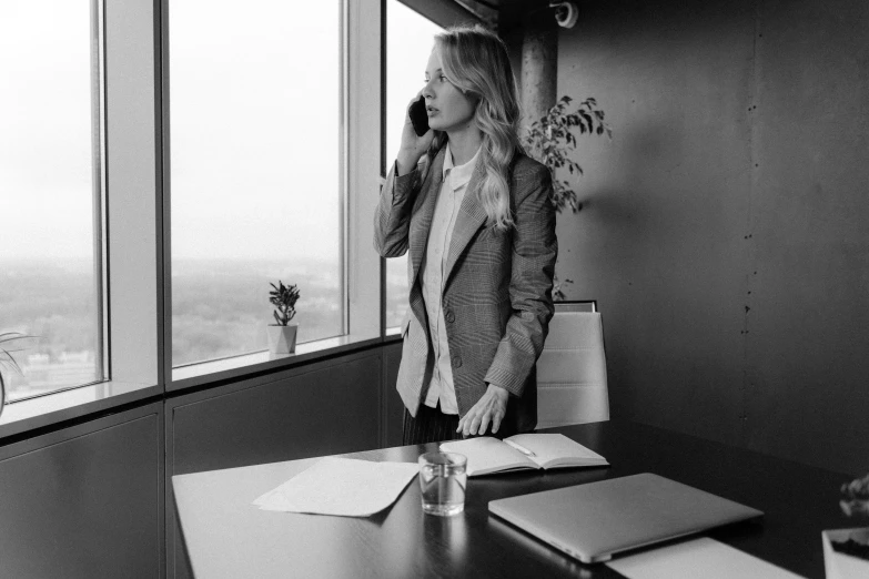 a woman talking on a phone standing near a window