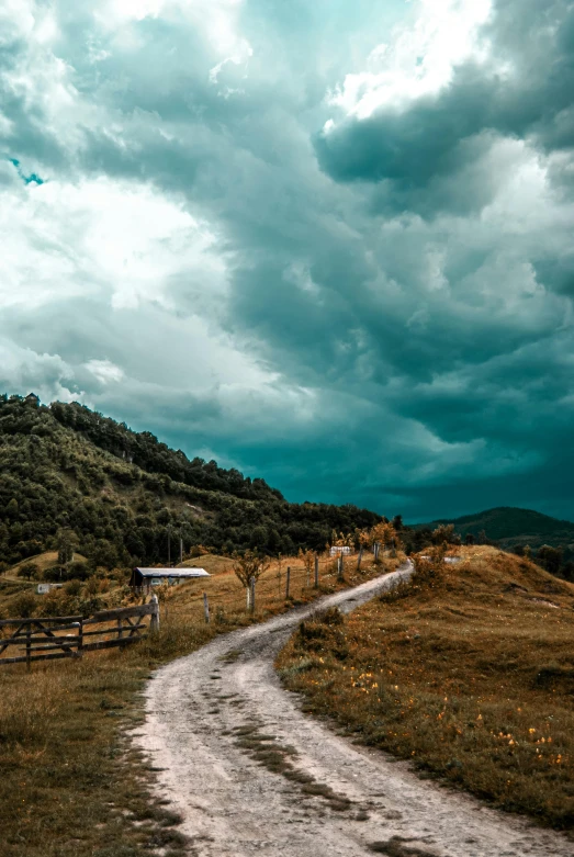 a rural dirt road that is surrounded by brown grass