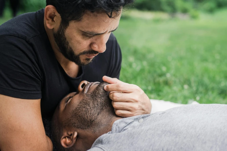 a man has his arm around another mans head and is touching his nose