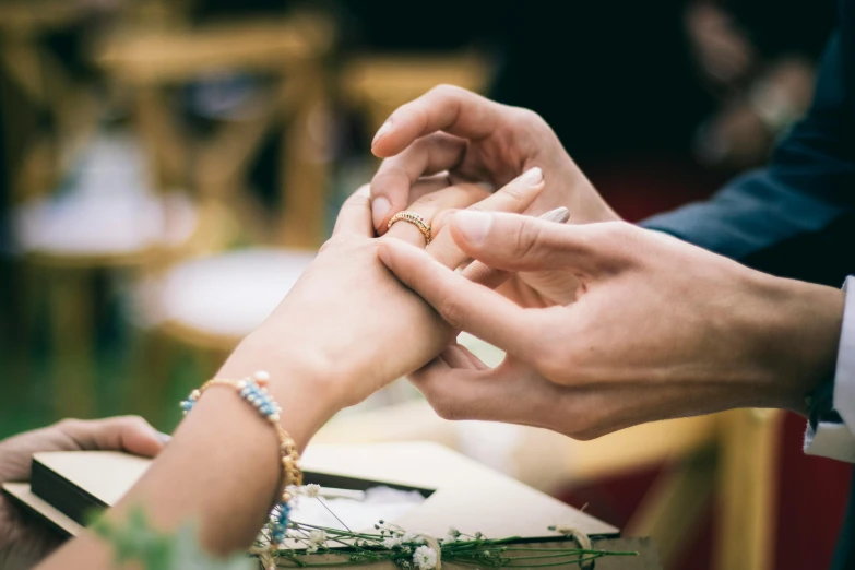 two people holding hands over each other at an outdoor wedding