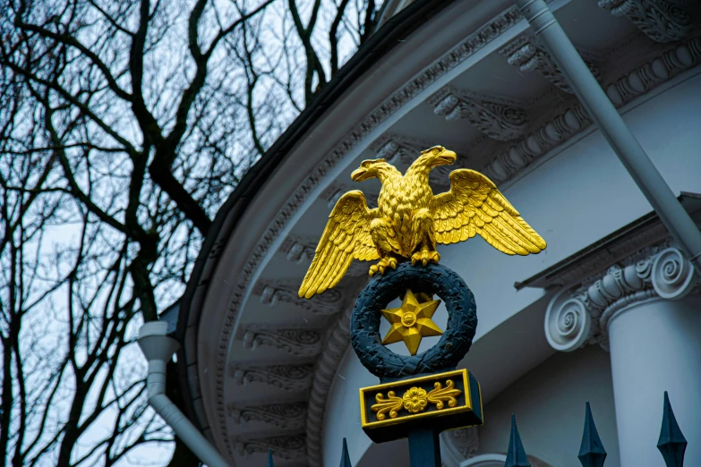 a metal eagle with a golden star on top next to a building