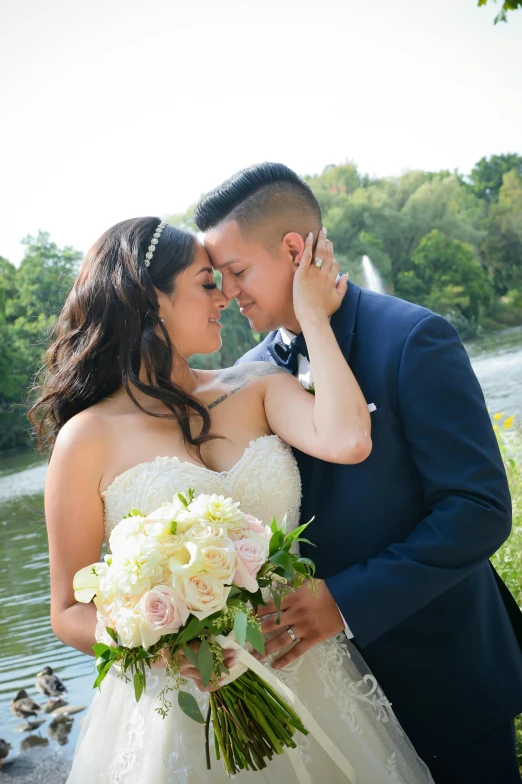 a bride and groom pose in front of a lake