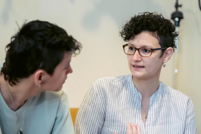 a woman sitting at a table talking to a man