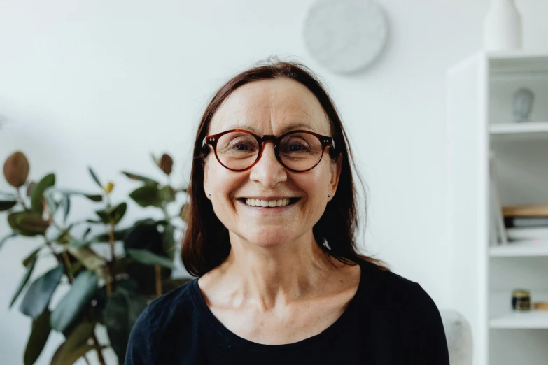 an older woman in glasses standing in front of a bookshelf