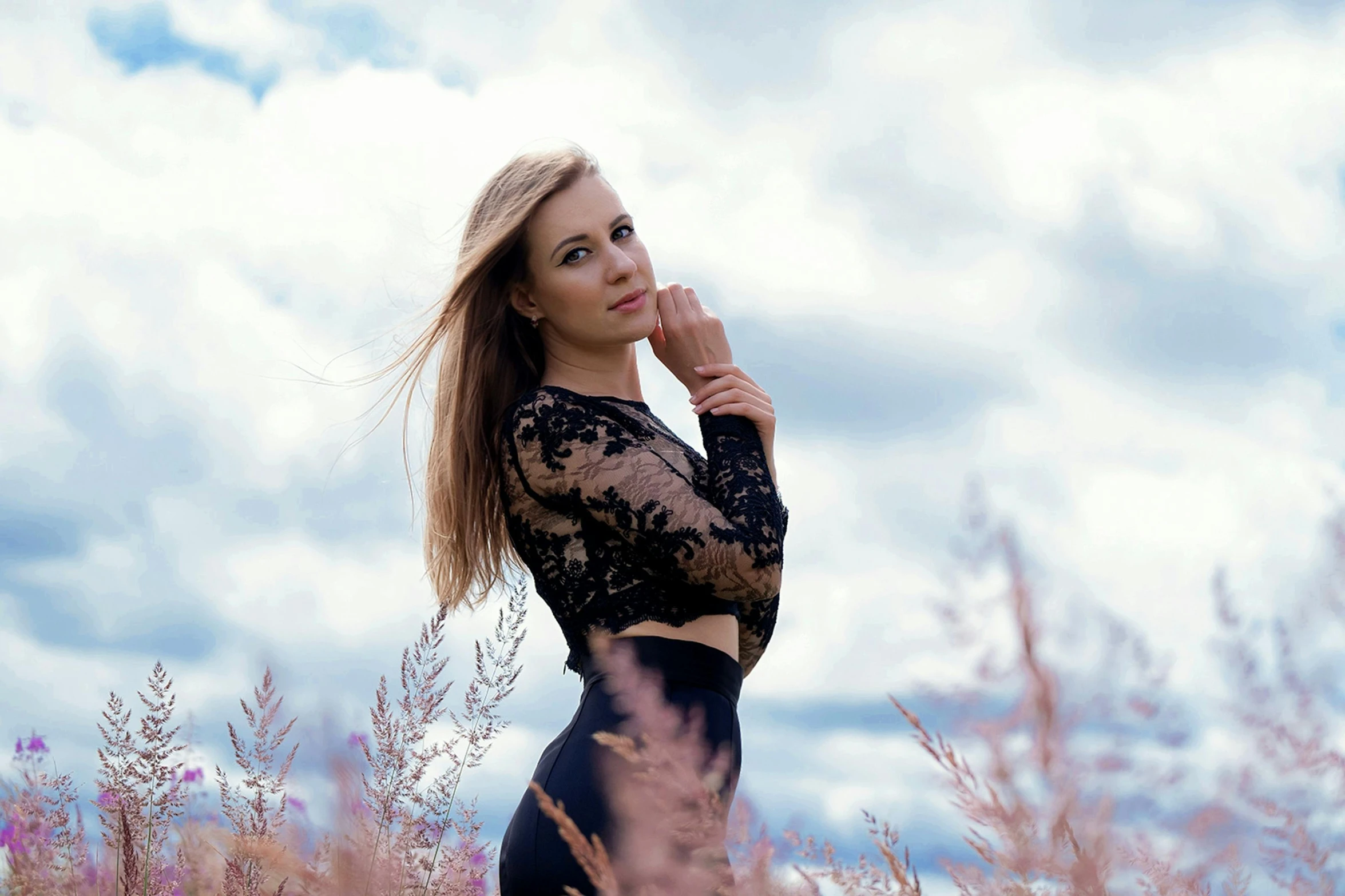 a beautiful woman in a black lace dress posing for the camera