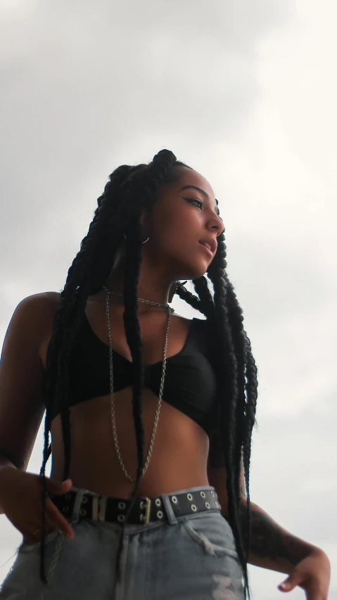 a girl with long hair in a  top and a chain is standing outside