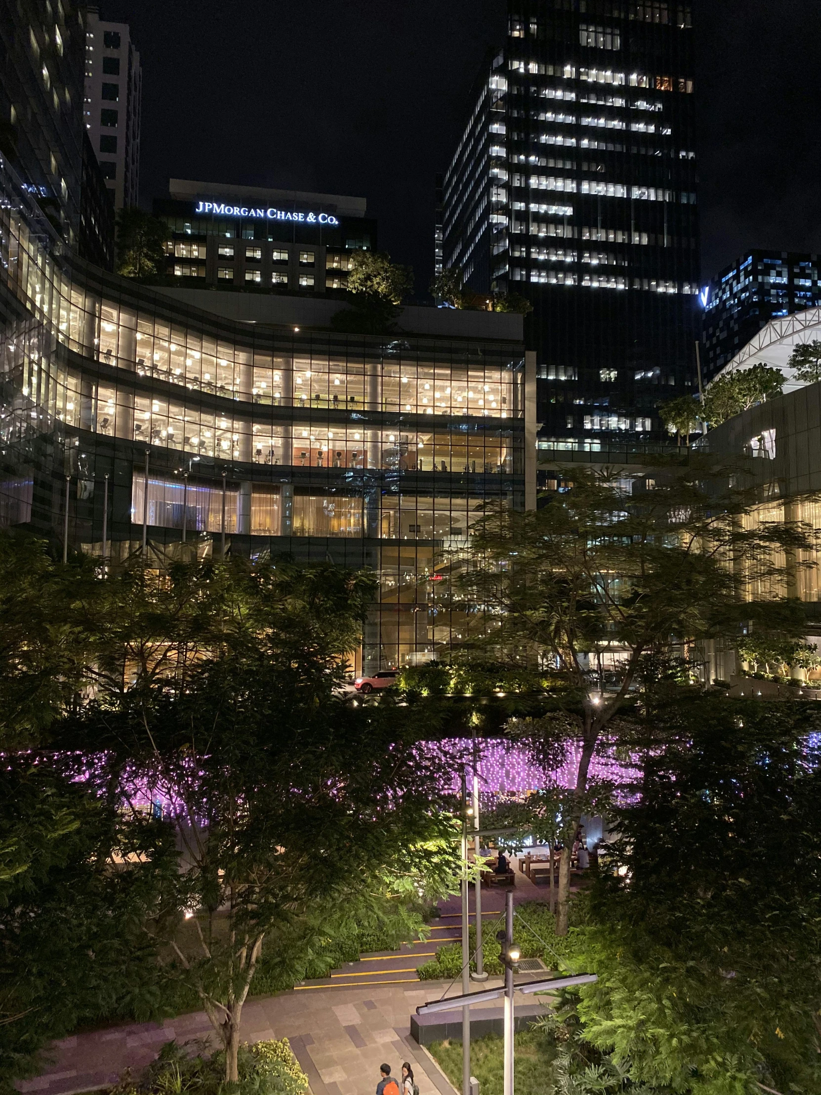 a large building at night with several people walking on the walkway