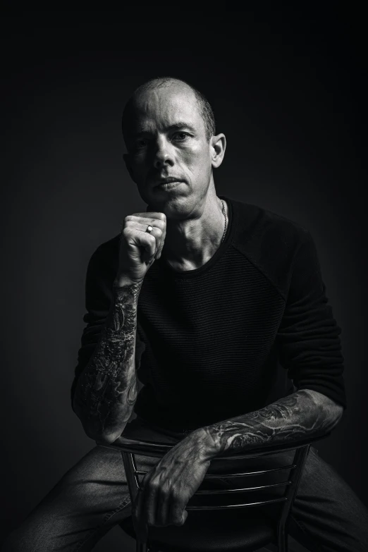 a man with tattooed arms is sitting in a chair