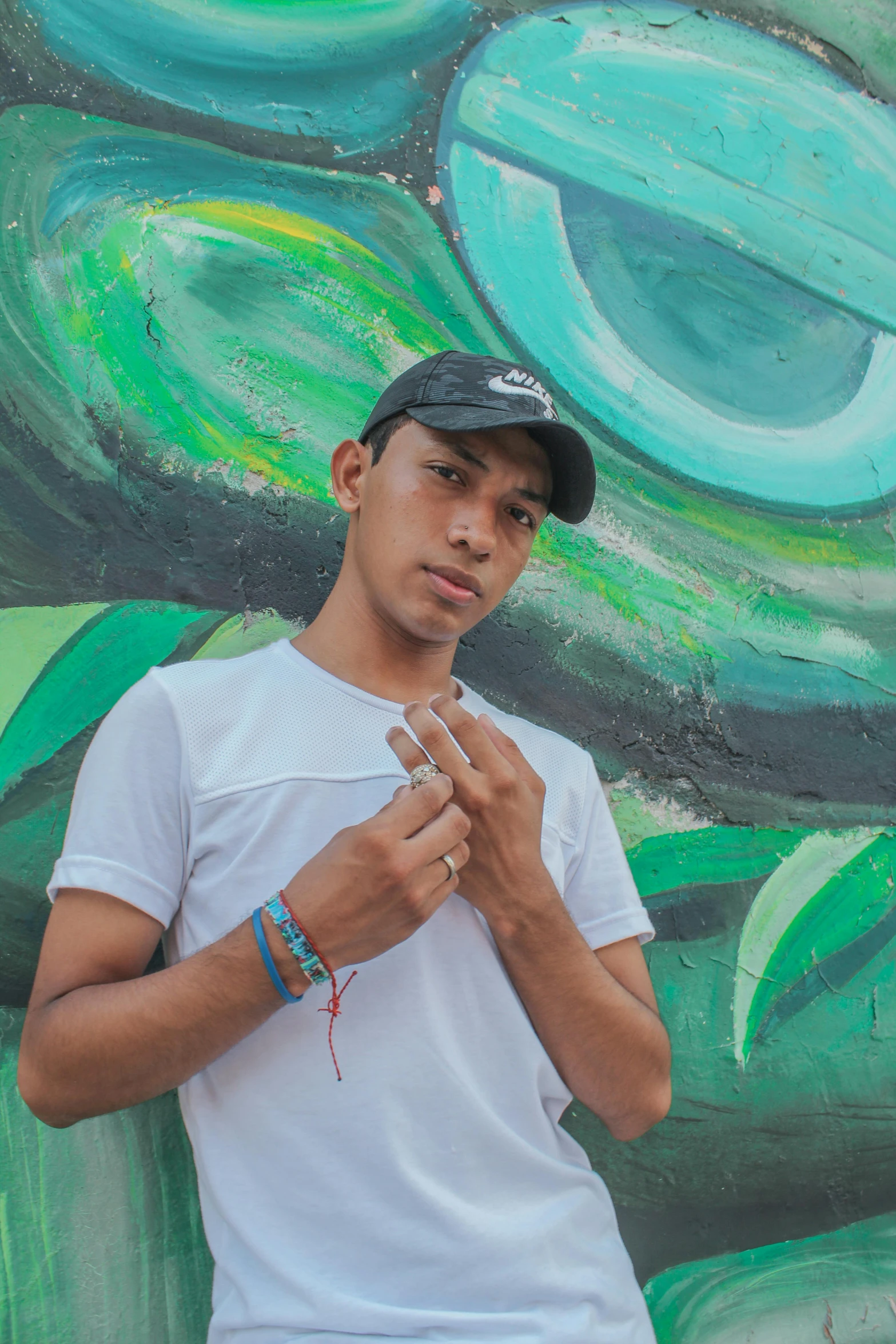 a man wearing a white t - shirt stands in front of a colorful mural