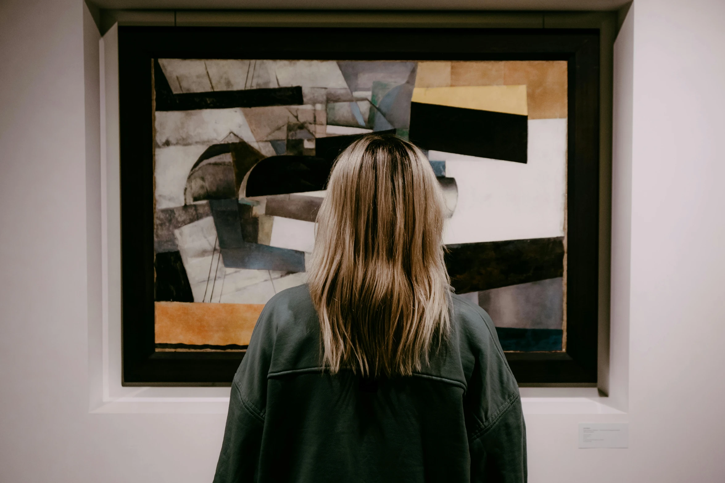 a woman with long hair standing in front of an art work