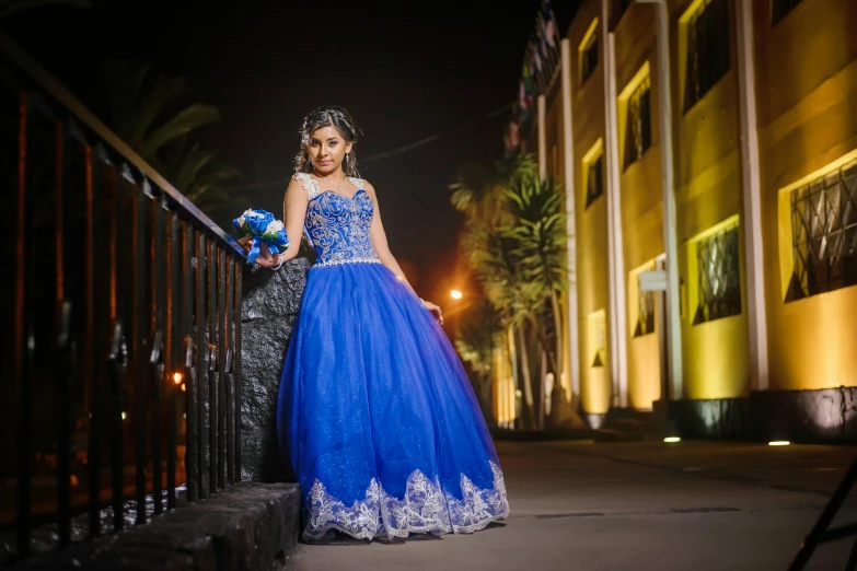 a beautiful woman dressed in an ornate blue gown and holding flowers