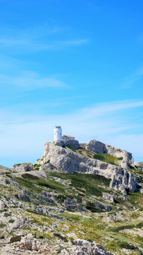 a white lighthouse perched on the side of a large hill