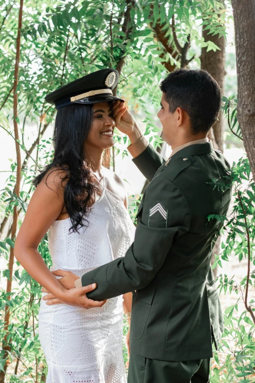 a bride and groom in a dress suit with a military hat and garb