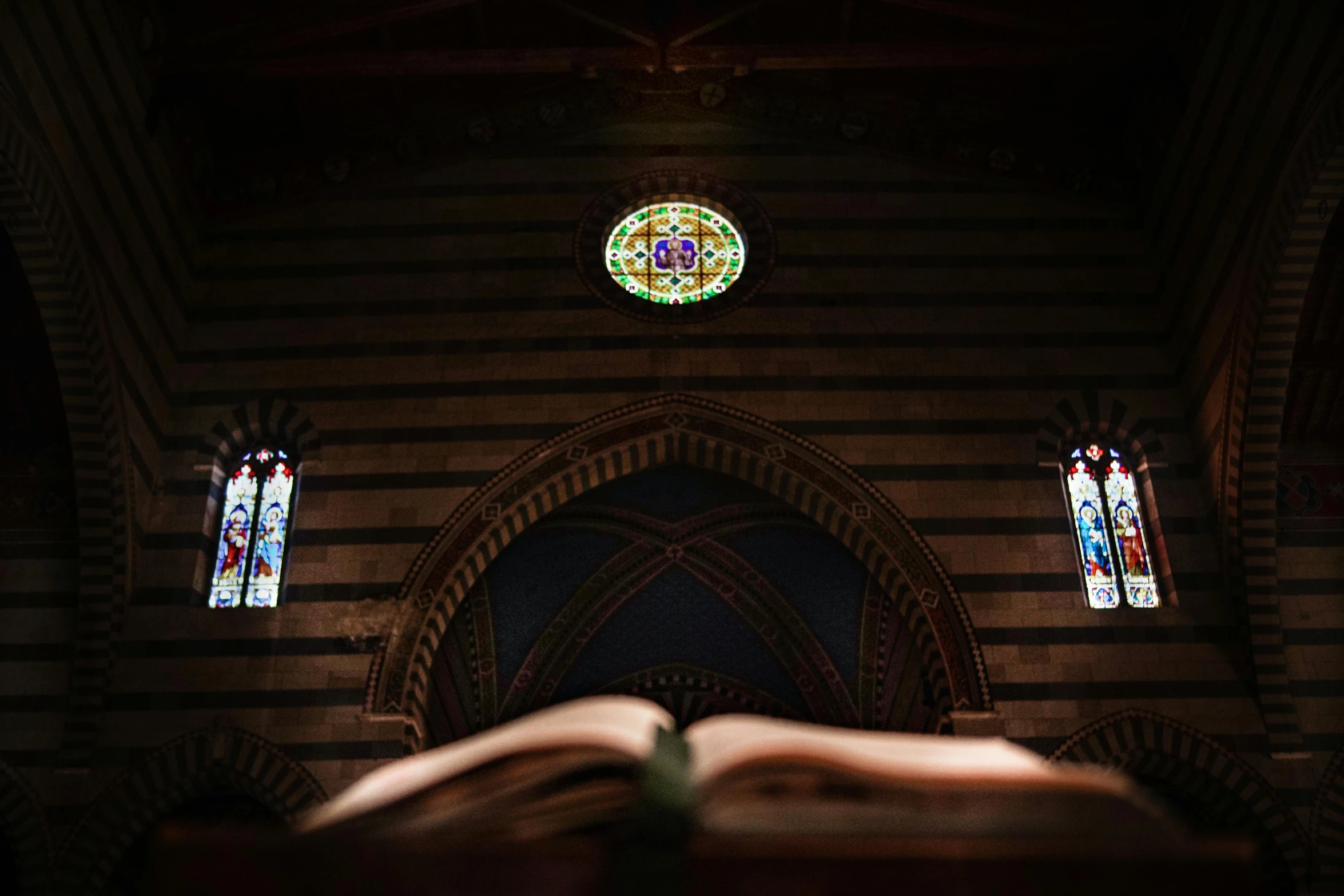 large book lying on floor with stained glass windows